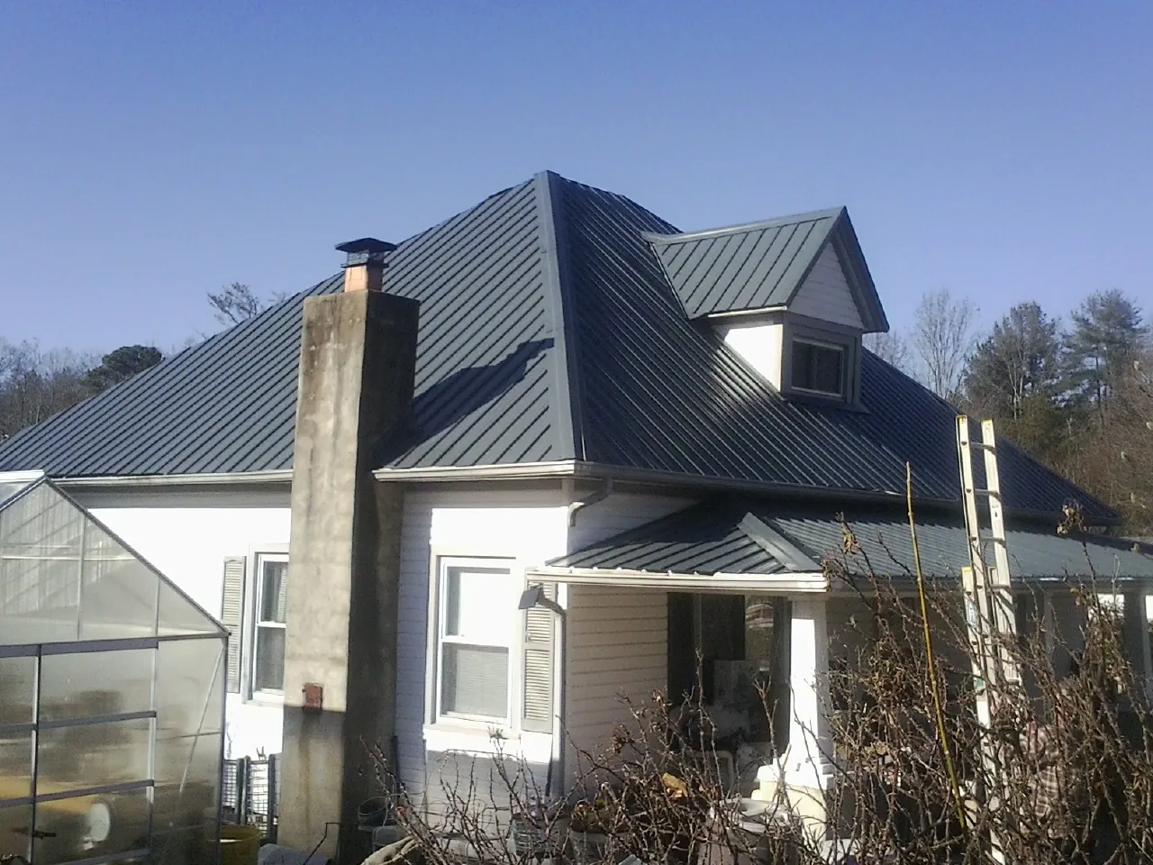 Dark blue standing seam metal roof on a white farmhouse with dormer — Slate & Tile Roof Repair by Roofing Brothers in Aubrey