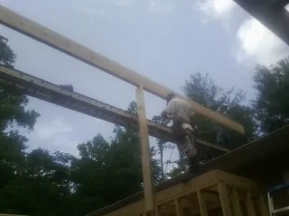 Carpenter setting a ridge beam over a new addition frame — Ice Dam Removal by Roofing Brothers in Aubrey