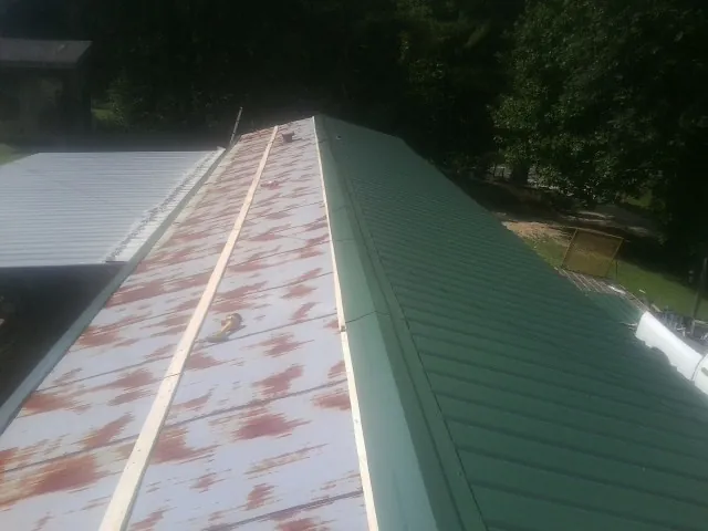 Old rusted panels beside newly installed green metal roofing — Wind Damage Roof Repair by Roofing Brothers in Aubrey