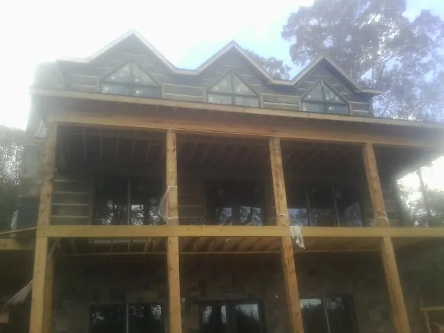Dormers and porch framing on a large log home under construction — Roof Coating work by our crew in Aubrey