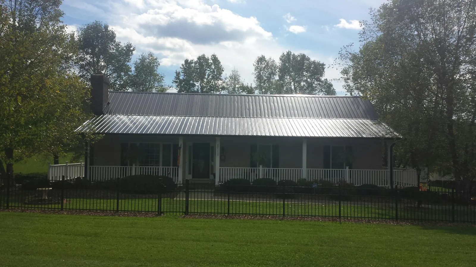 Gray metal roof on a brick ranch with a full width front porch — Gutter Guard Installation work by our crew in Aubrey